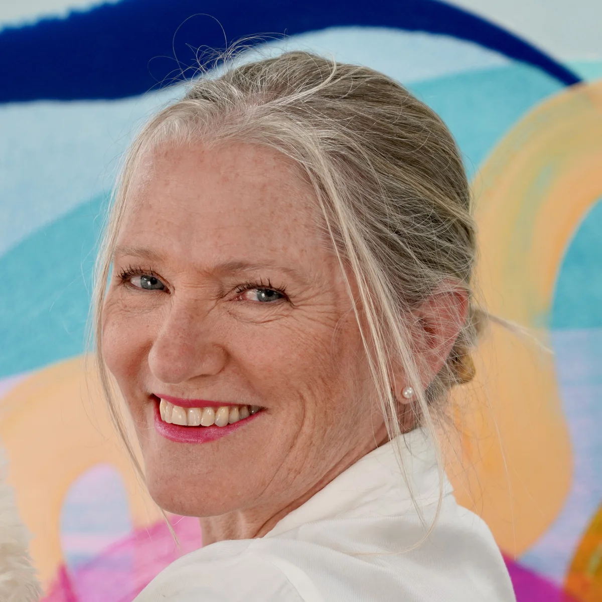 Claire Desjardins in front of colourful artwork.