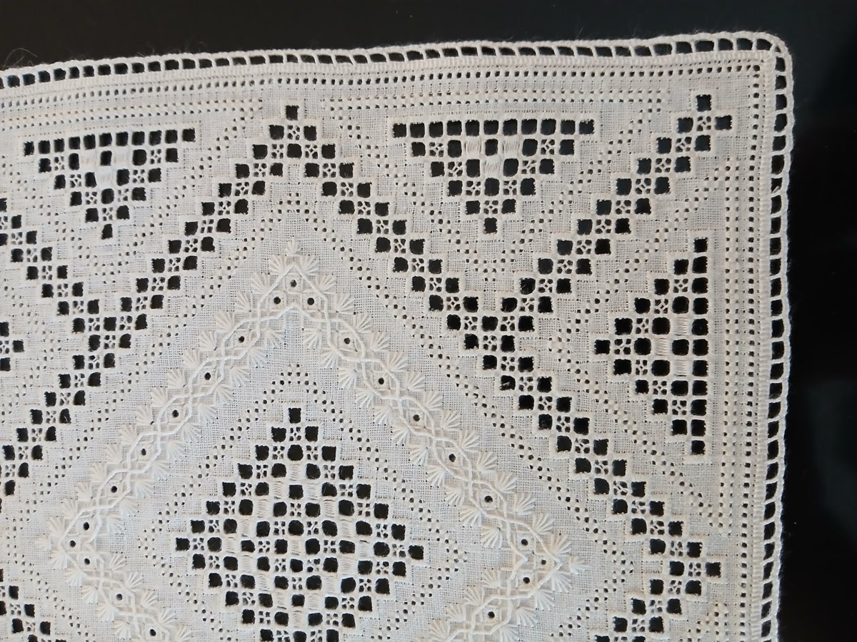 White-on-white Lefkara needlework — hemstitched cutwork and satin-stitch fills on fine linen.